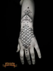 Tatouage symbolique en entrelacs sur la main réalisé par Baybay Blondy