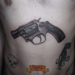 Revolver réaliste tatoué sur torse par Jérémy Fatneedle