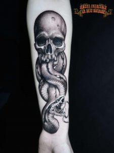 Crâne et serpent réalistes tatoués sur bras par Jérémy Fatneedle