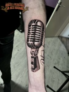 Microphone vintage réaliste tatoué sur bras par Jérémy Fatneedle