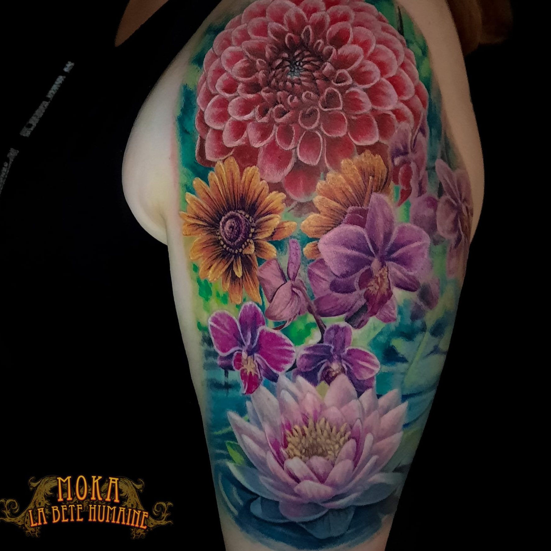 Vibrant half-sleeve tattoo of a large pink dahlia, yellow sunflowers, purple orchids, and a pink water lily on the upper arm with green-blue background
