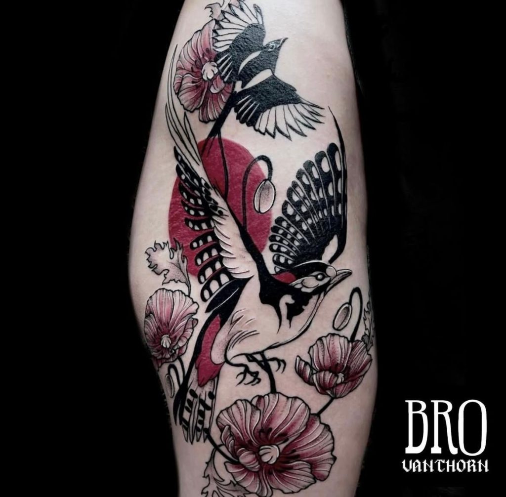 Tatouage sur la cuisse sketchy : deux pies en vol entourées de coquelicots et de feuillages en noir et rouge, réalisé par Bro Vanthorn