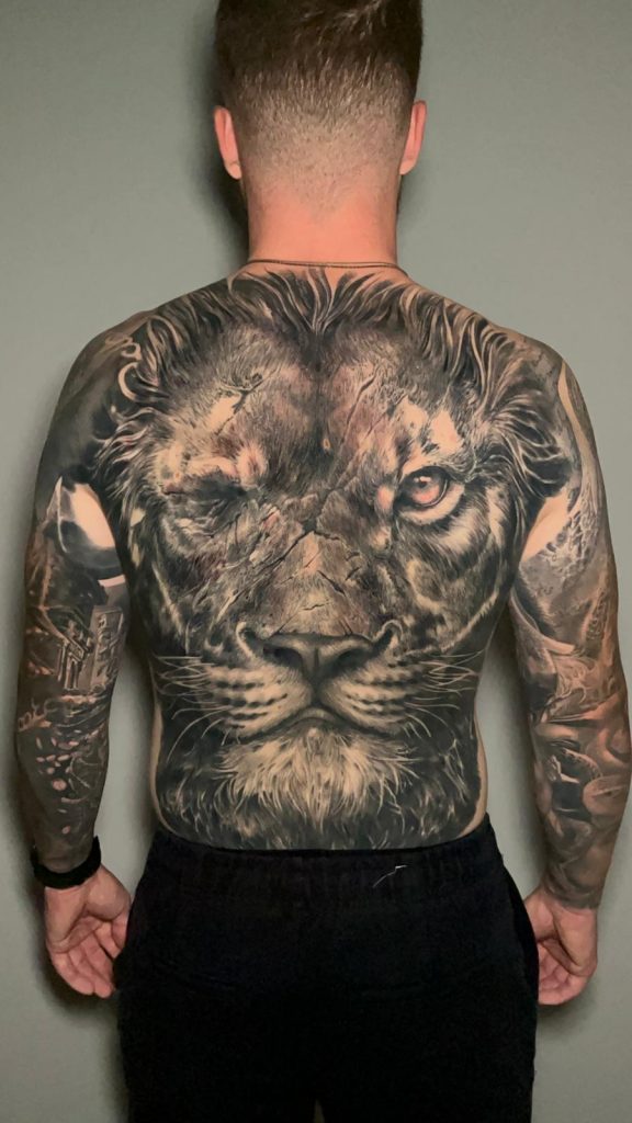 Full back tattoo of a lion in realism by Alvaro Sanchez